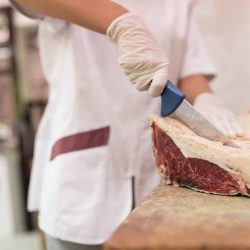 Butcher woman cutting meat.