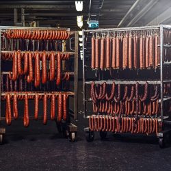 Sausages on racks in a storage room in meat processing factory.